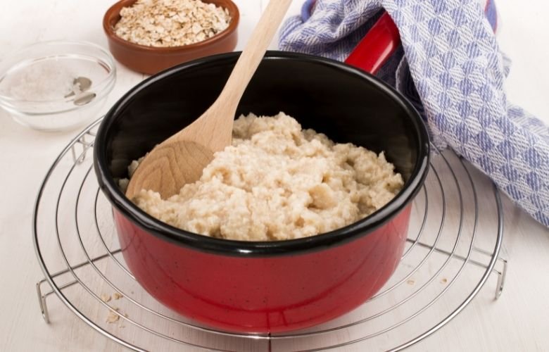 panela vermelha com arroz em cima de um descanso em aramado