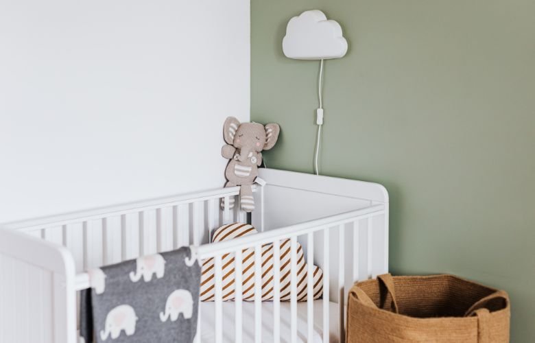 Quarto de bebê masculino decorado com pelúcia de elefante e luminária de nuvem, criando um ambiente aconchegante e temático.